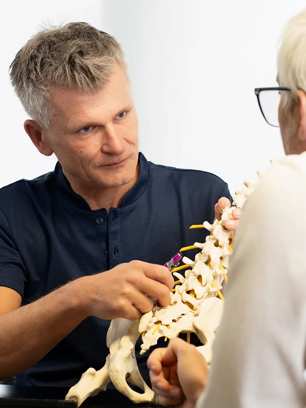 Dr. Willibald Walter erklärt einer Patientin die Wirbelsäule am Modell